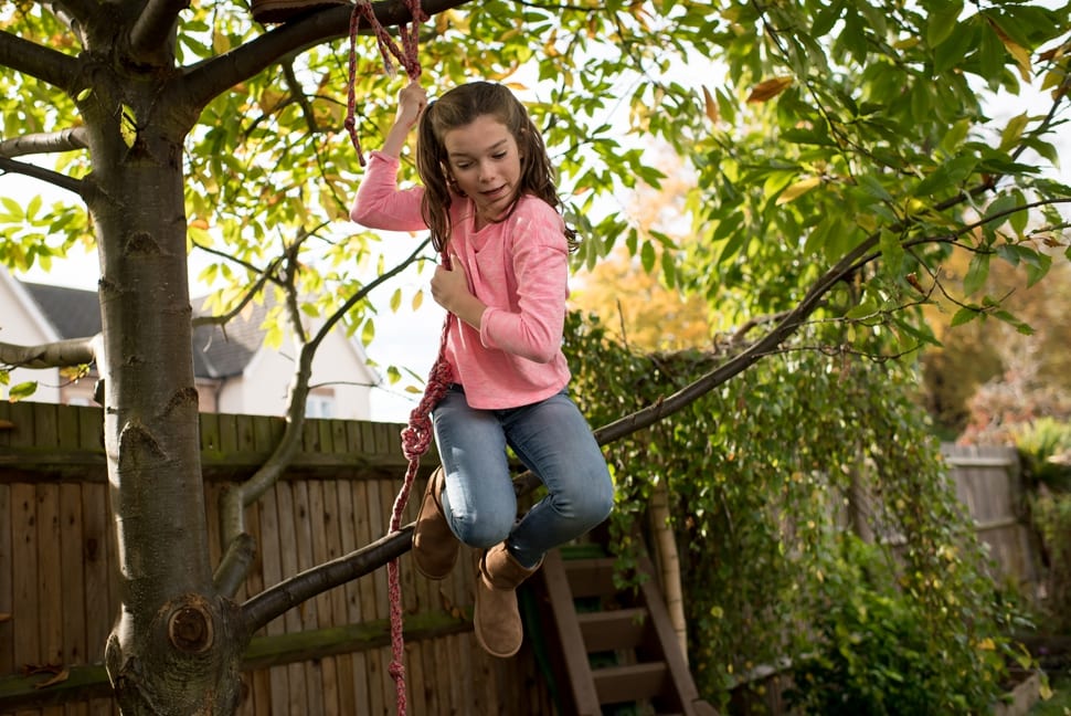 girl jumping down from a tree using a rope