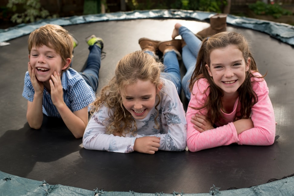 family photoshoot with kids lying on trampoline laughing