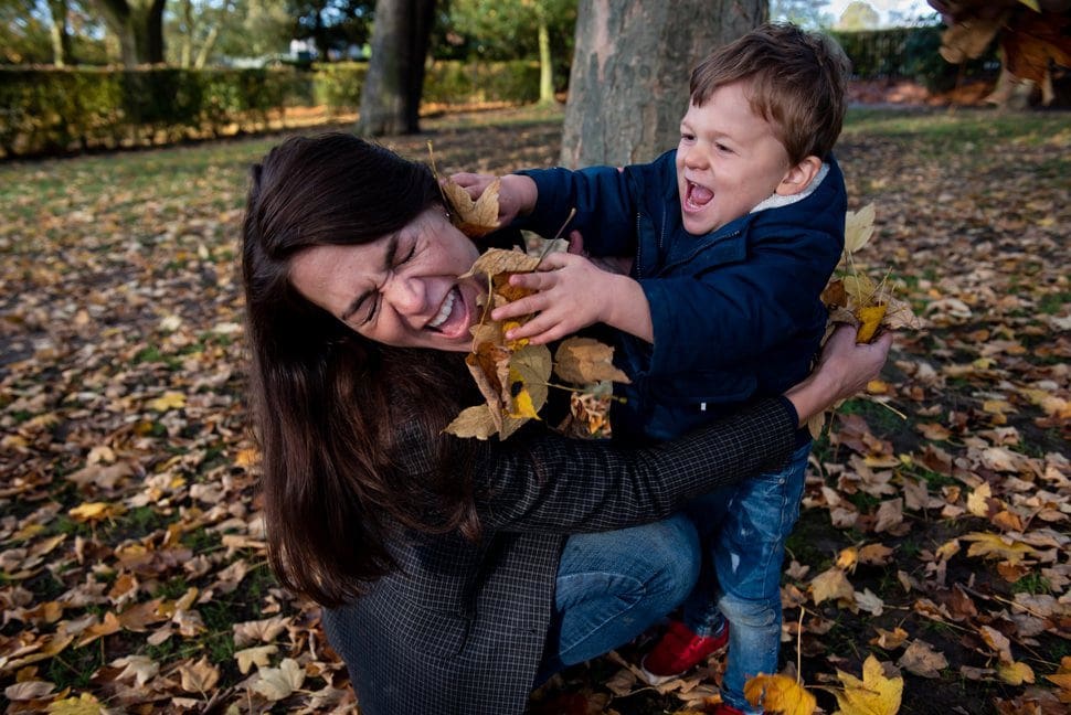 son throwing leaves at laughing mum in st albans park