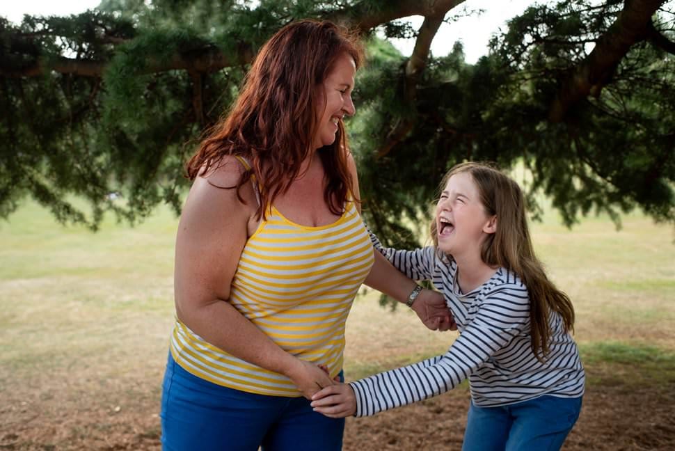 teen and mum laughing together in the park