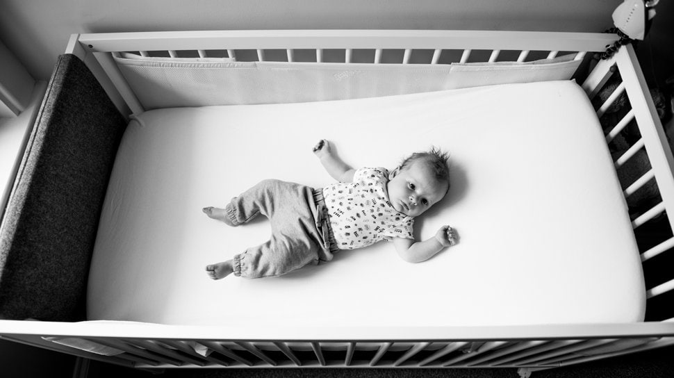 young baby lying in cot newborn photoshoot