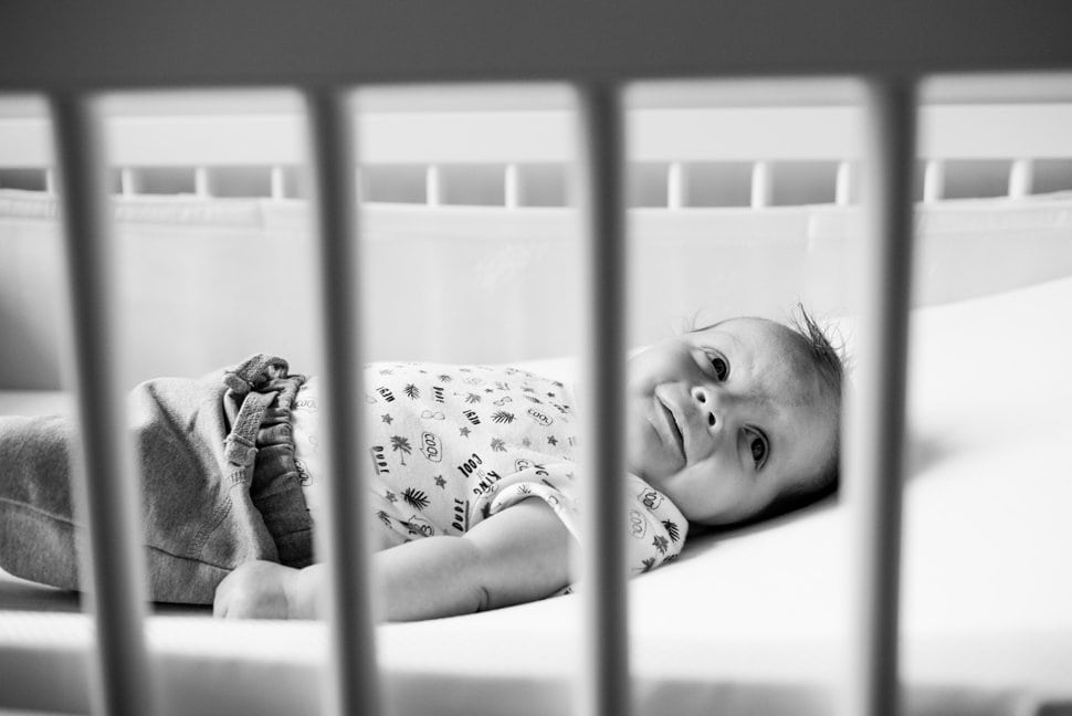 3 month old smiling through cot bars during family photos