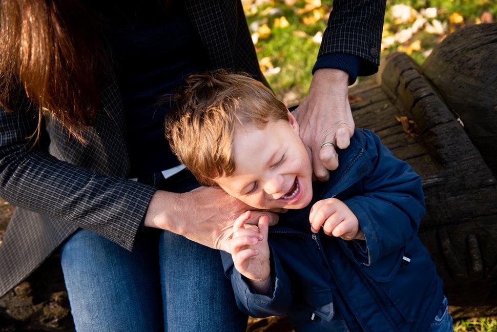mum's hands ticking giggling son on his neck