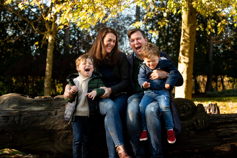family photos with laughing St Albans family sitting on log