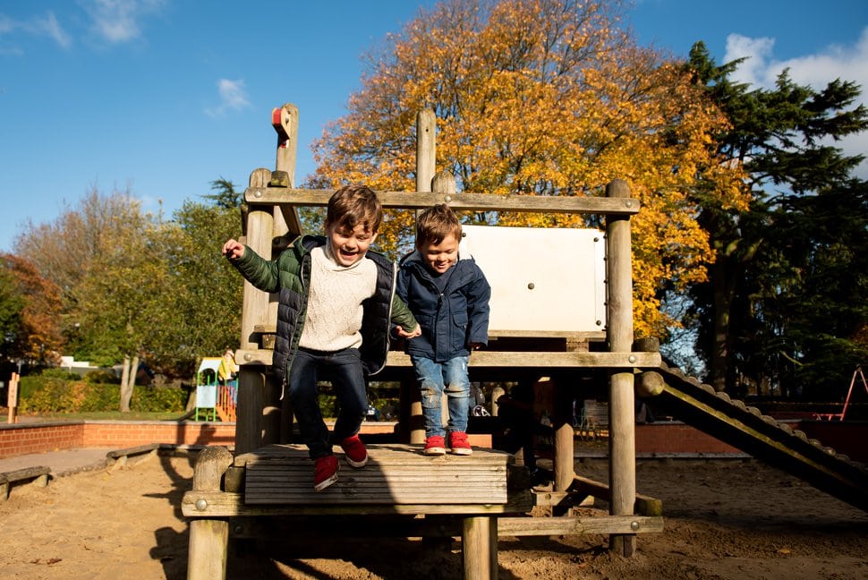 brothers hold hands and jump from wooden climbing frame in St Albans photoshoot