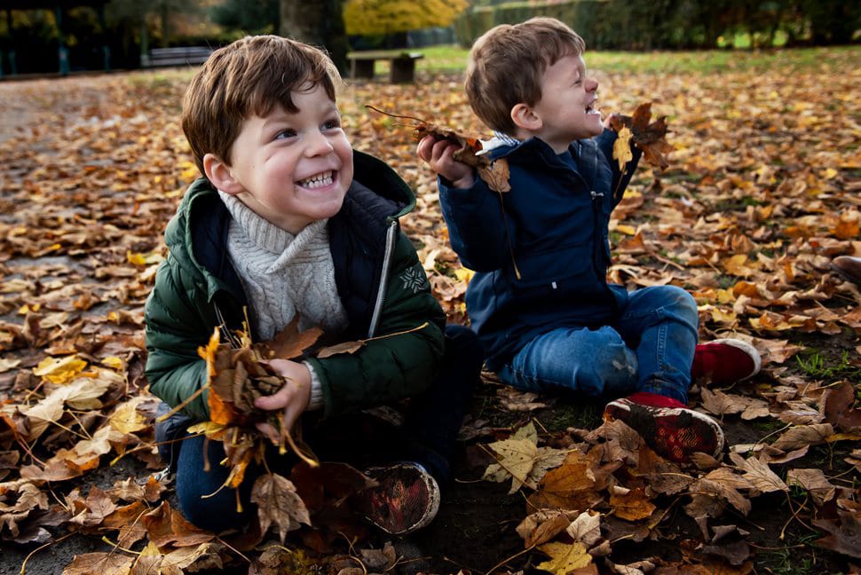 brothers getting handfuls of leaves ready for leaf fight during family photoshoot