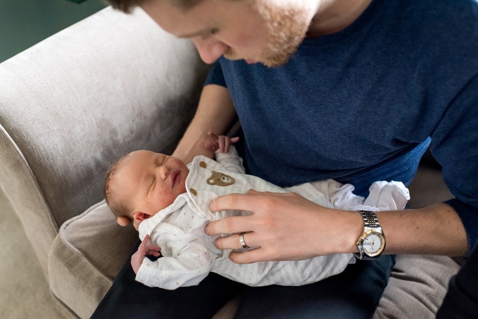 new dad cuddling baby girl during newborn photoshoot