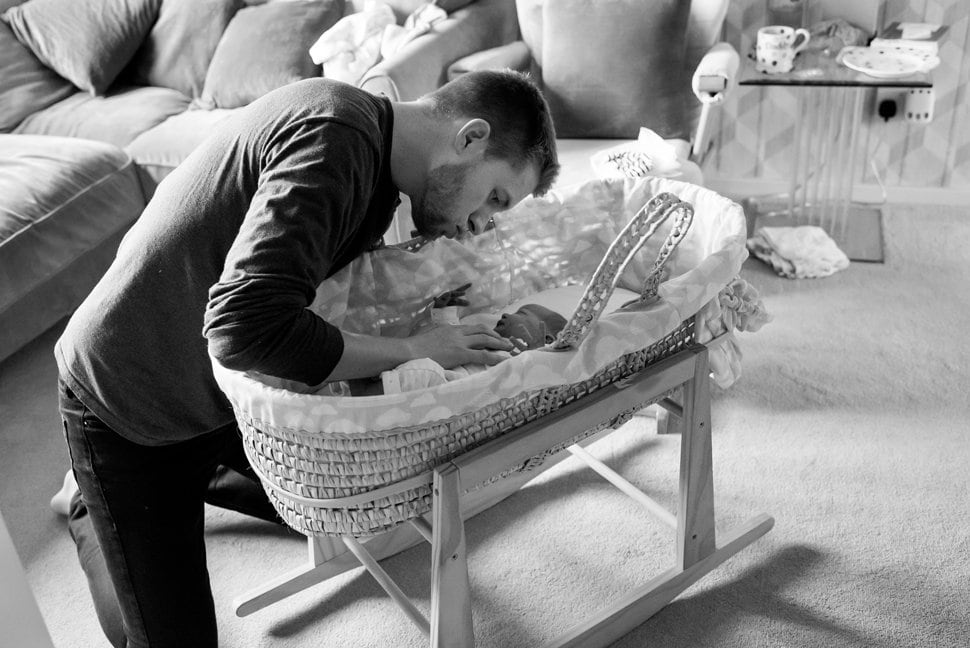 dad settling baby into bassinet