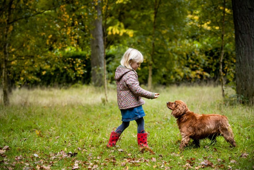 blonde girl feeds family dog during photoshoot