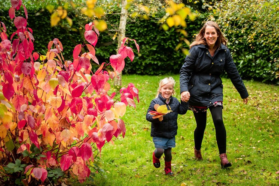 mum and daughter run around autumn trees