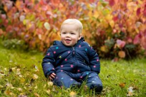 snuggled baby in front of autumn trees