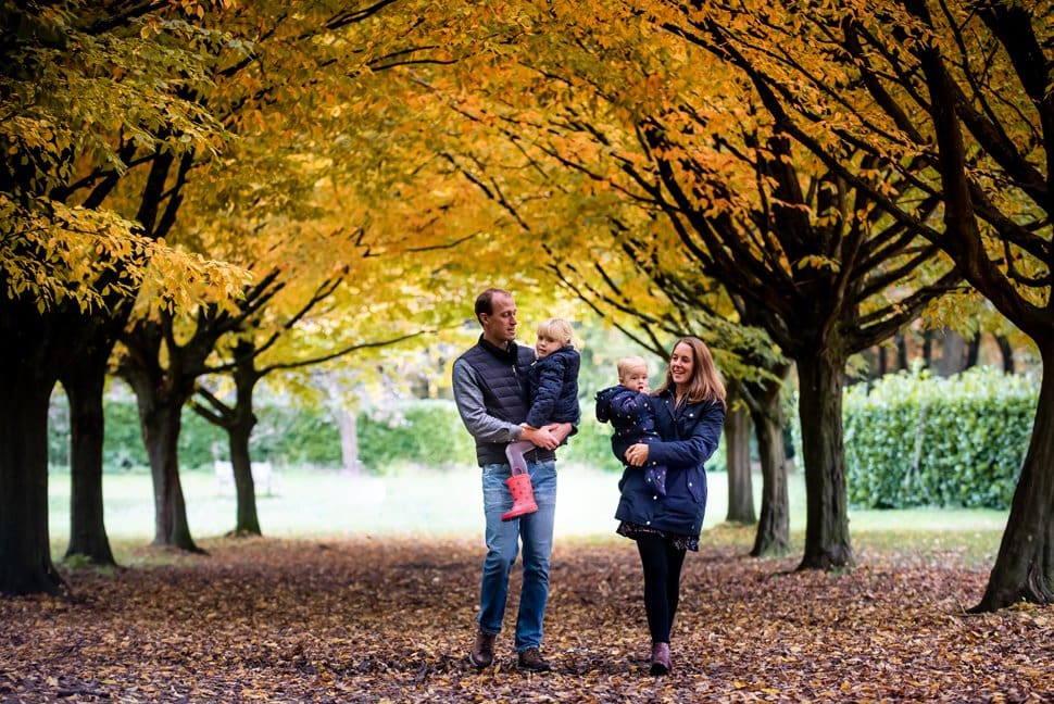 family walk through autumn trees on photoshoot