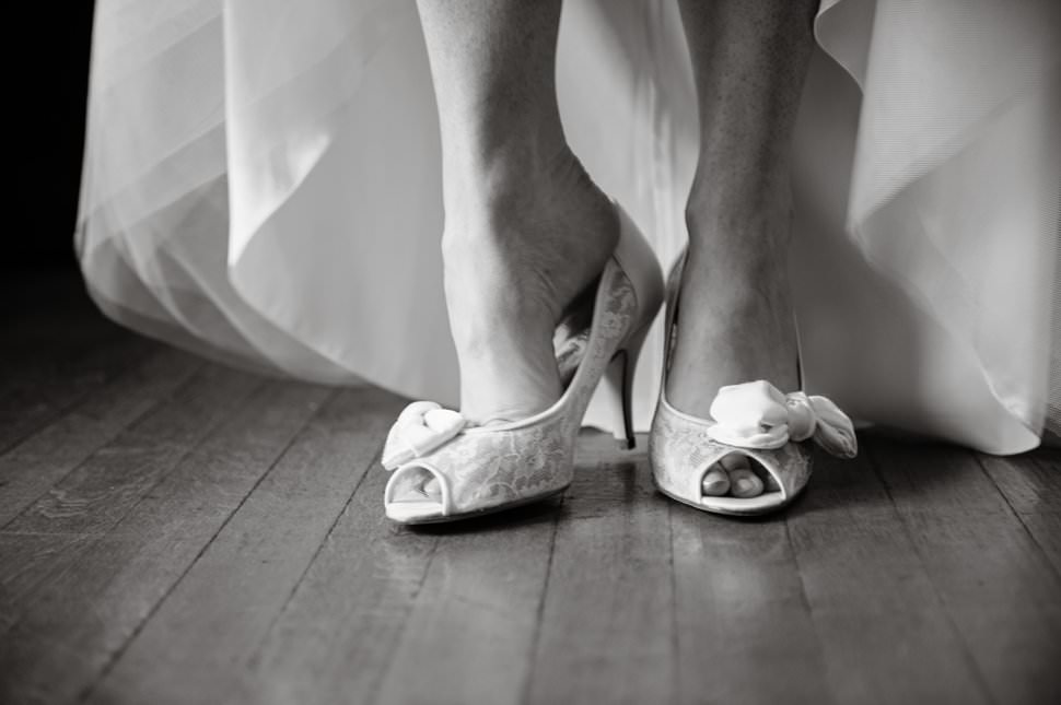 bride putting on white wedding shoes with bow