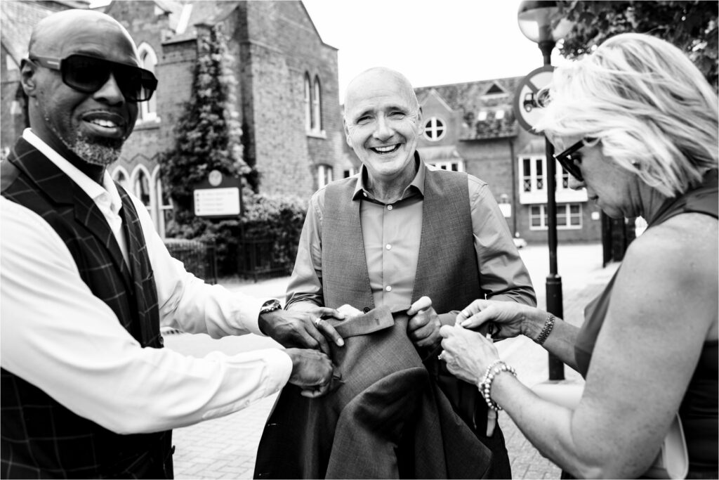 Groom gets help with his suit jacket from friends outside St Albans Register Office