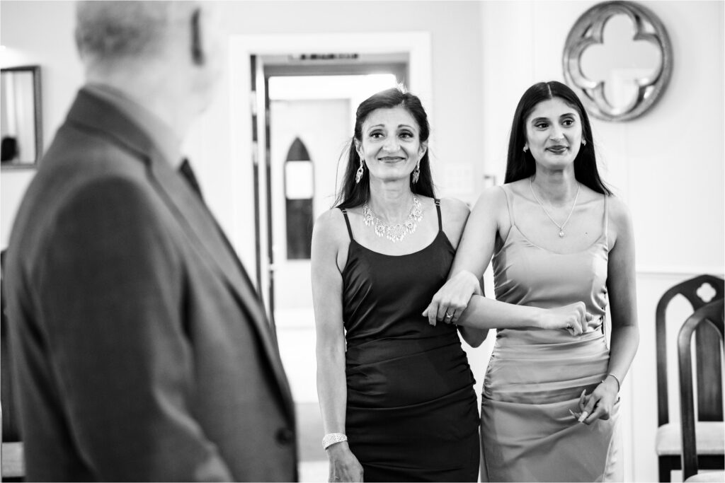 Bride is walked down aisle by daughter towards groom