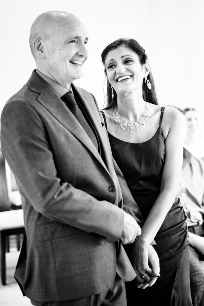 Bride looks adoringly at groom during wedding ceremony while holding hands