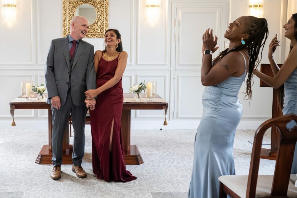Bride and groom get cheered at top of aisle in grey register office room