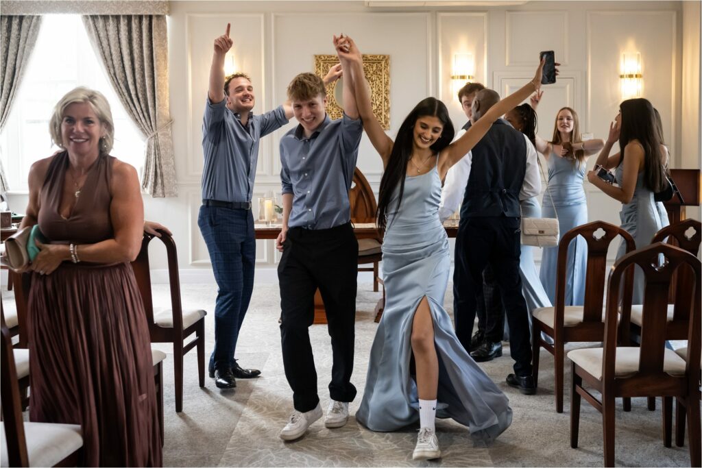 Bridesmaid in powder blue dress dances back down aisle with groomsman