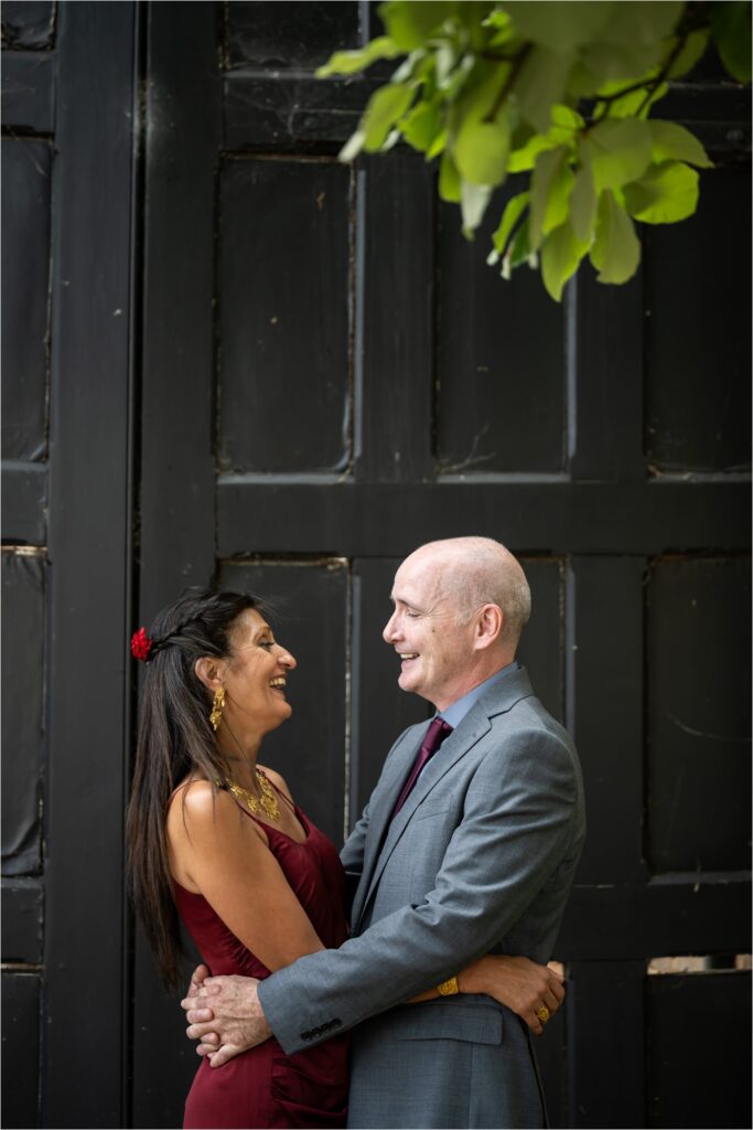 Bride and groom embrace in front of large black doors at St Albans Register Office