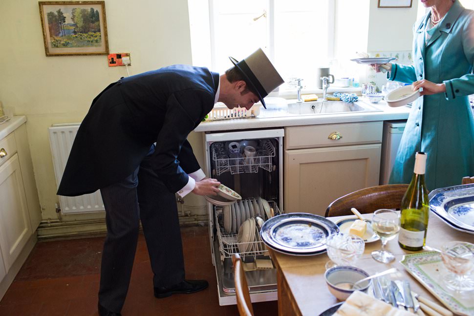 Groom loading dishwasher in tophat and tails