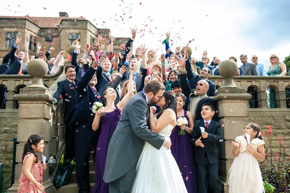 All guests throw confetti over a kissing couple at their Fanhams Hall wedding.