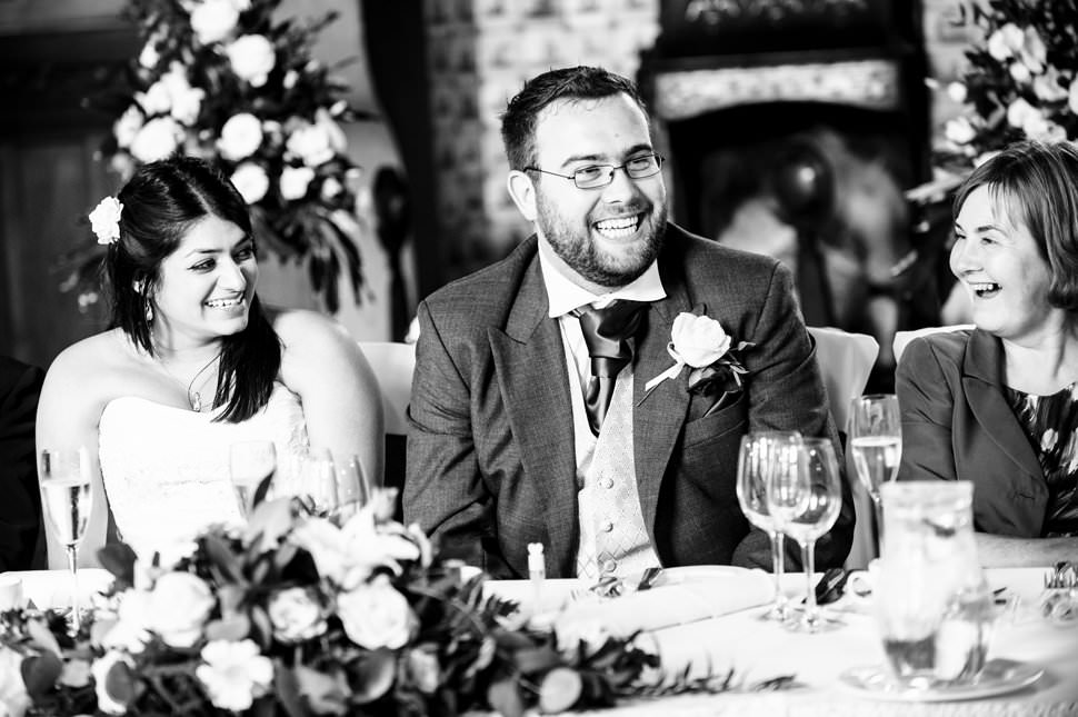 Bride and groom laugh during funny wedding speeches.