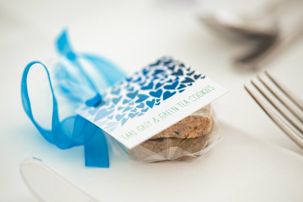 Homemade biscuit wedding favours with blue ribbon and printed sign
