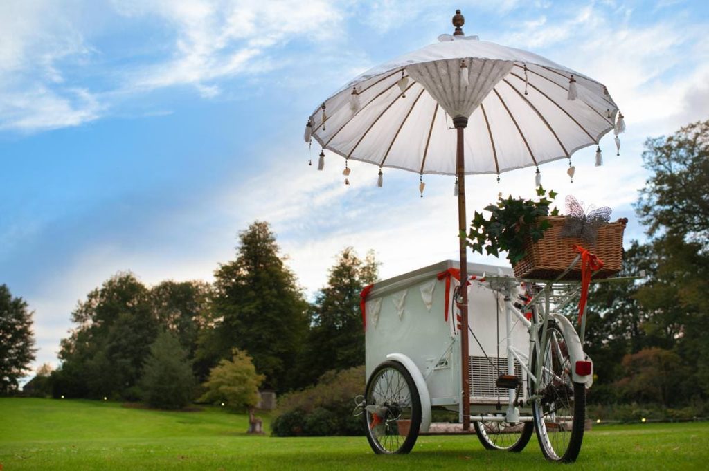 Vintage ice cream bicycle cart at a wedding in front of sunset sky