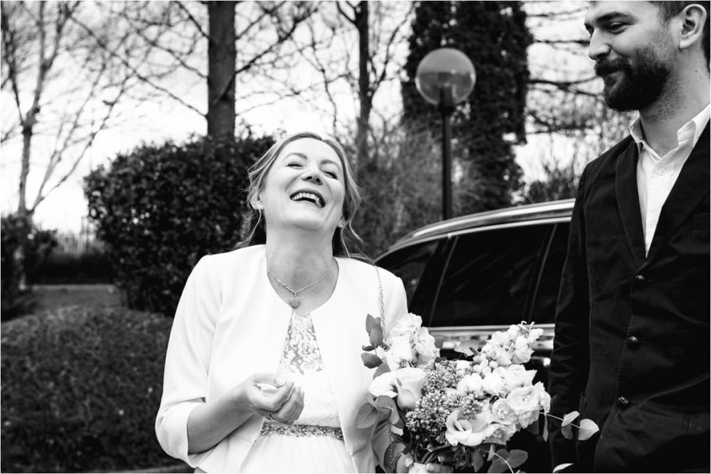 Bride laughs after getting out of wedding car.