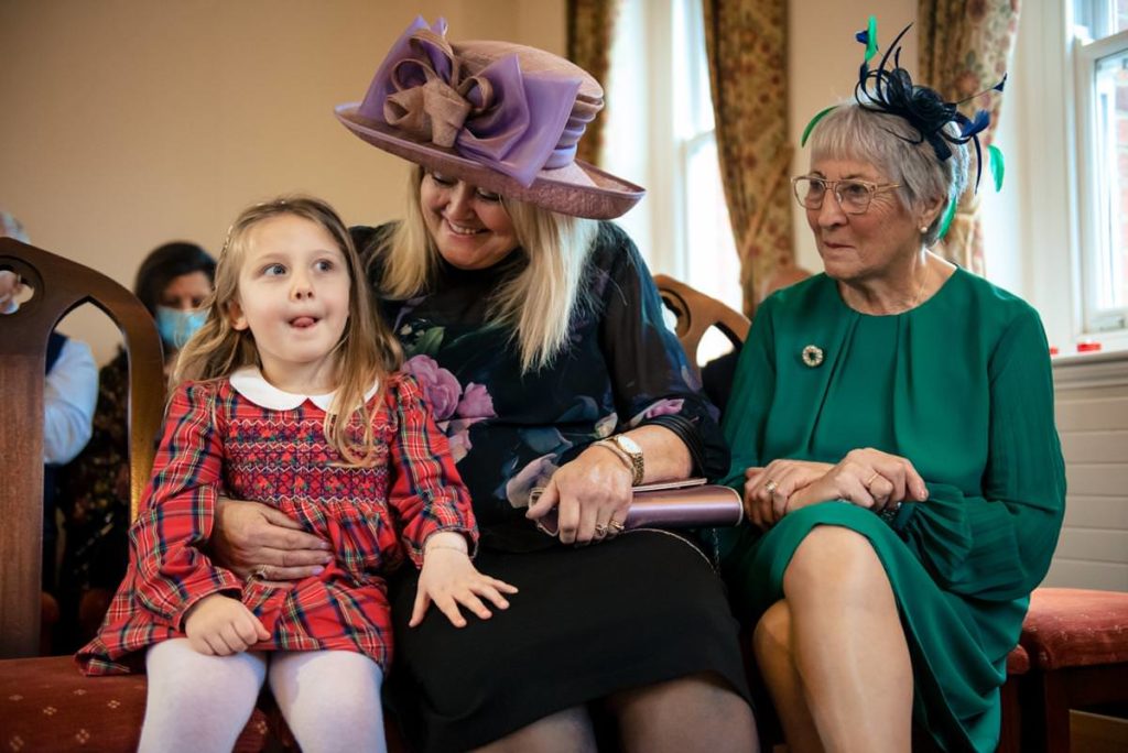 Little girl sits with other guests at St Albans Registry Office wedding.