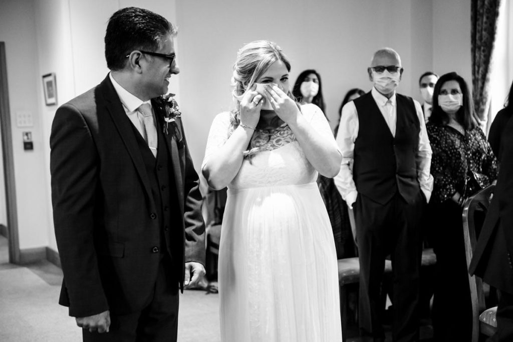 An emotional bride wipes away tears during a St Albans Registry Office wedding.