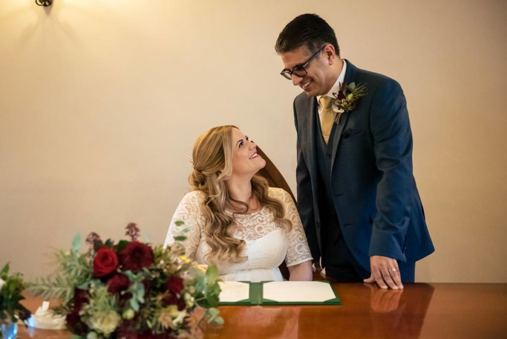 A bride smiles up at a groom after signing the register in St Albans Registry Office.