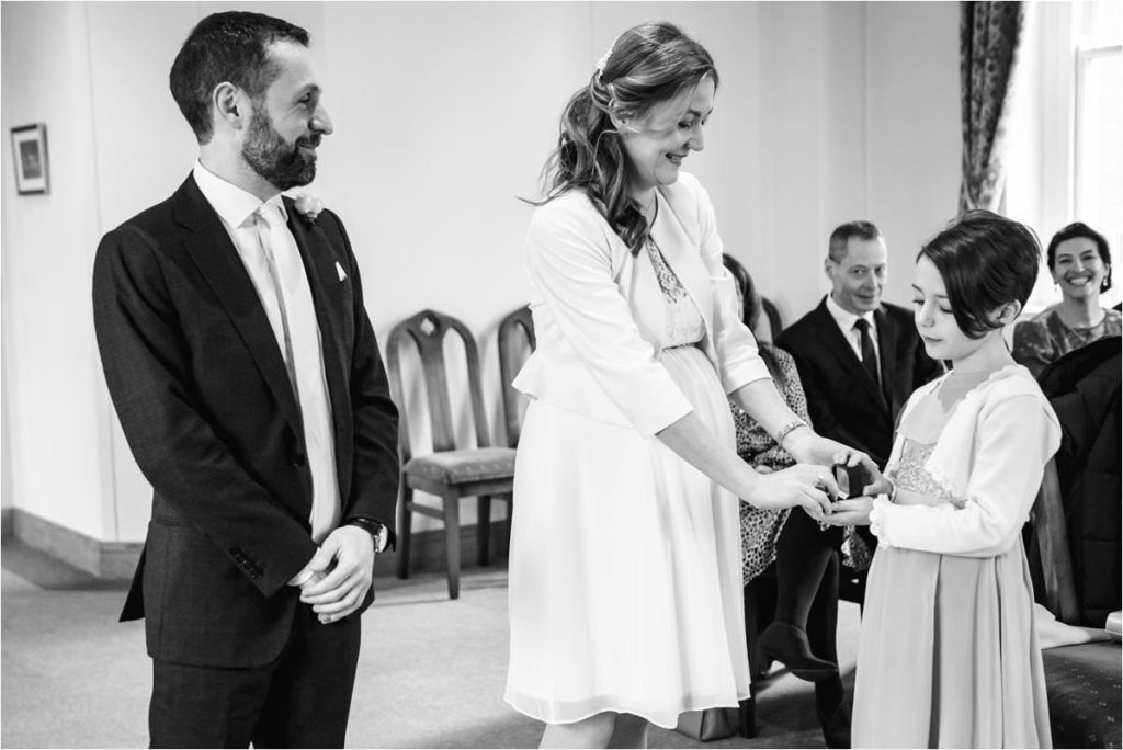 Bride takes ring from flowergirl at St Albans Registry Office wedding.