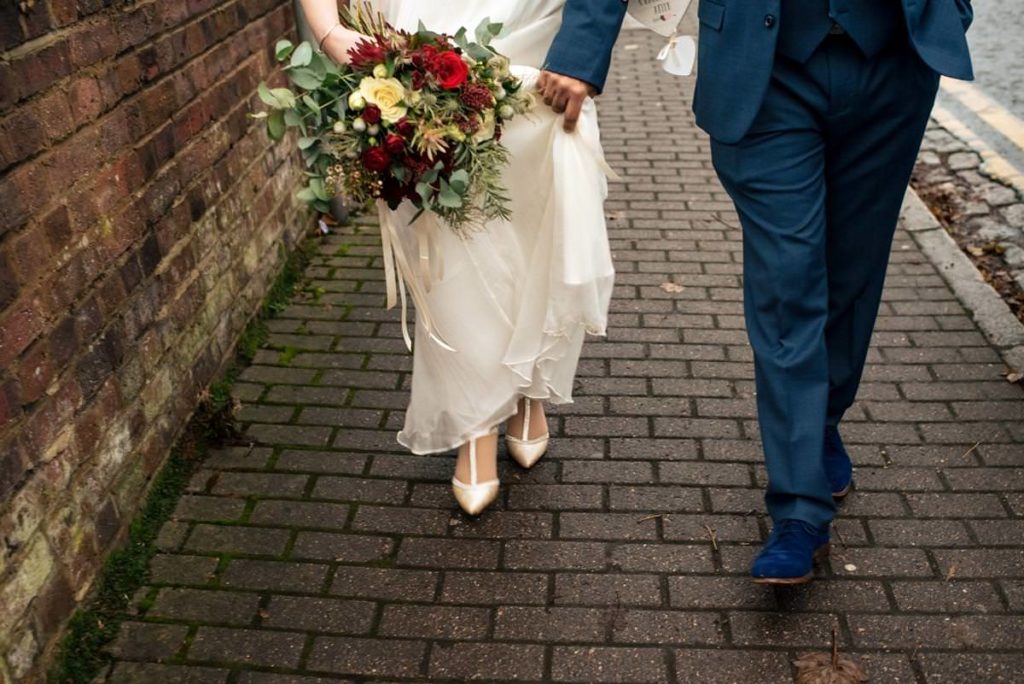 Bride and groom walking showing their wedding shoes.