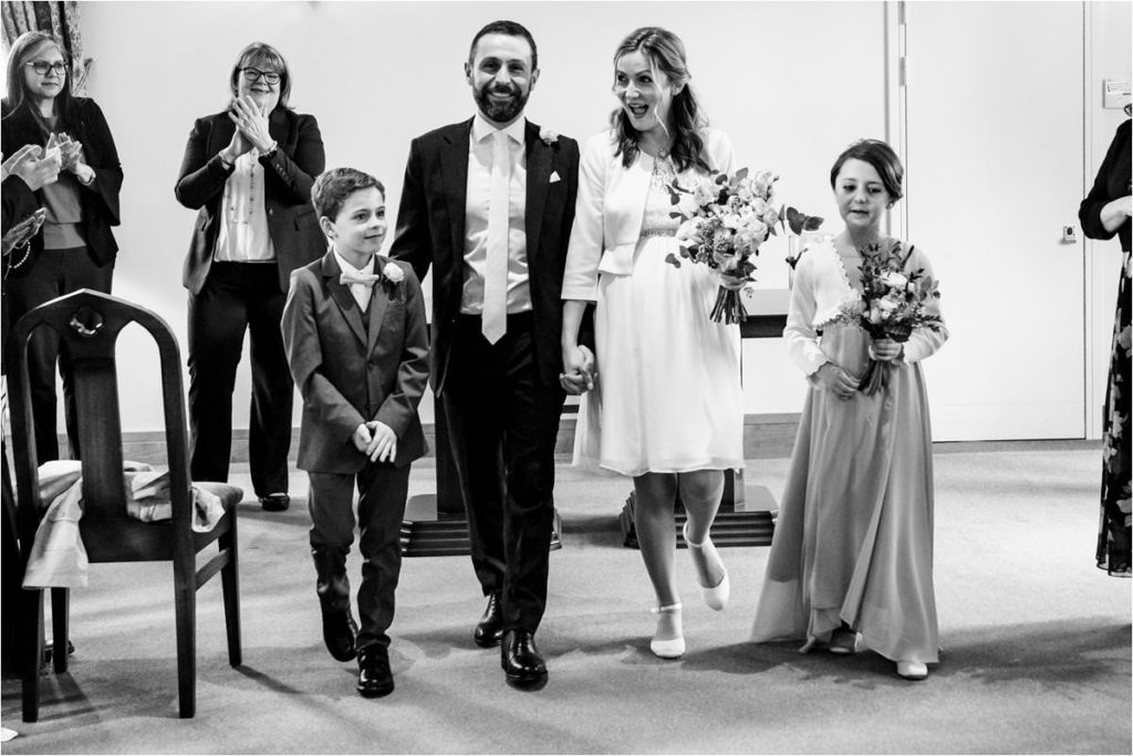 Bride and Groom leave St Albans Registry Office wedding ceremony with their children.