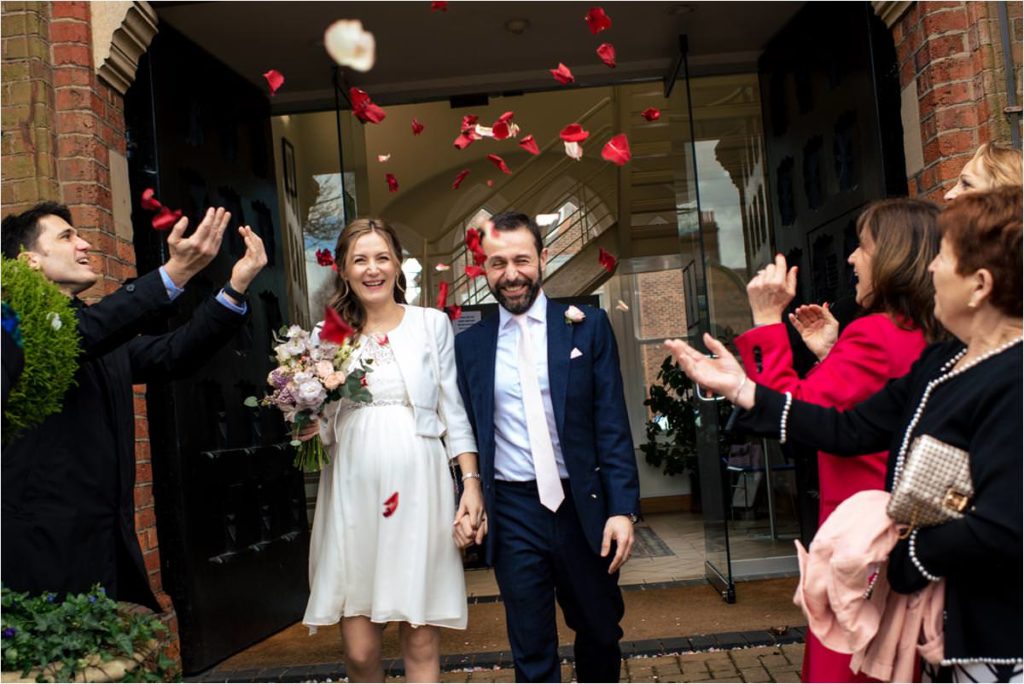 Guests throw petal confetti on bride and groom outside St Albans Registry Office.