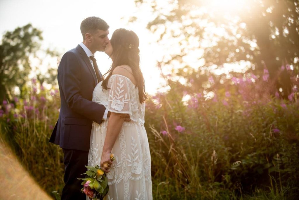 Hazy summer evening light with kissing bride and groom