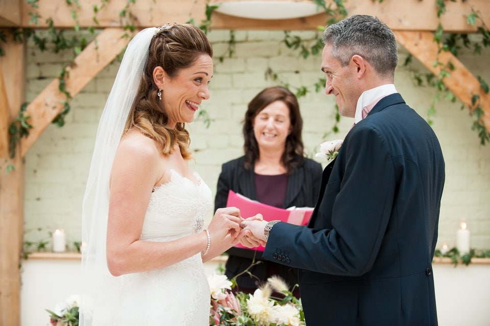 Gaynes Park couple excitedly smile while exchanging wedding rings in the Orangery