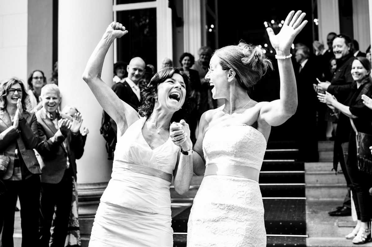 Two cheering brides leave wedding ceremony