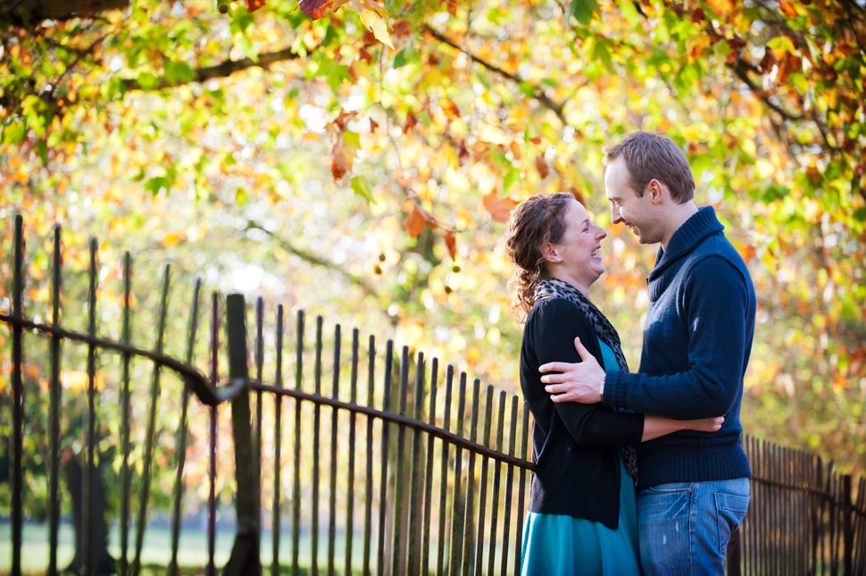 Couple hug and laugh by autumn leaves and Oxford railings