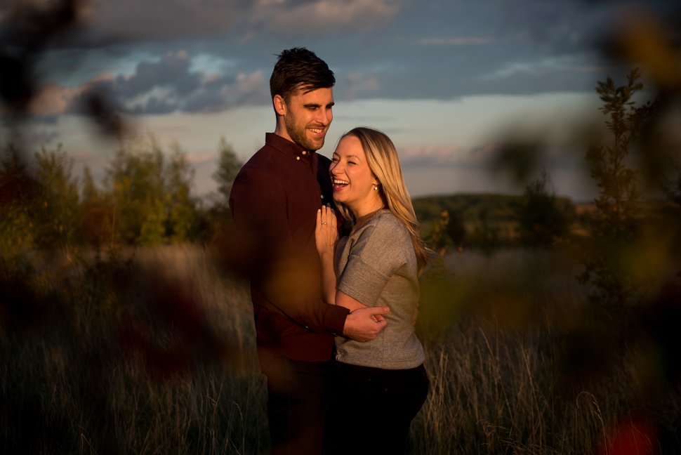 Cuddling couple laugh in fading evening light