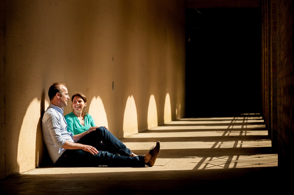 Couple sit on floor in sun patch by arches