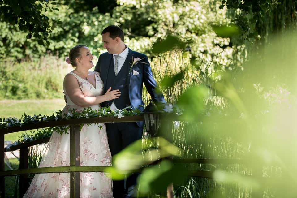 Bride and groom standing smiling on bridge at Hertfordshire wedding