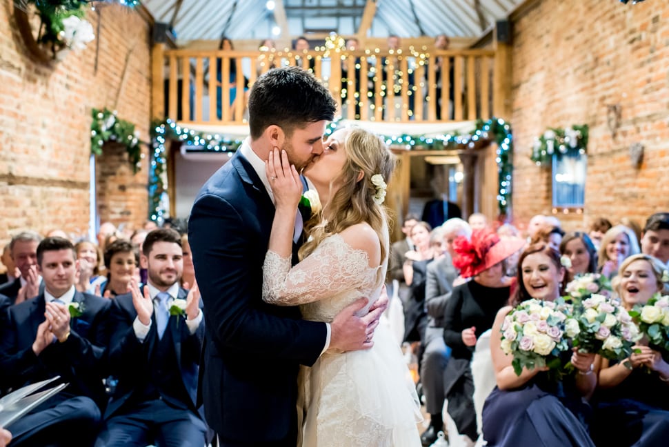 Bride and groom kiss during winter wedding ceremony at Tewinbury Farm