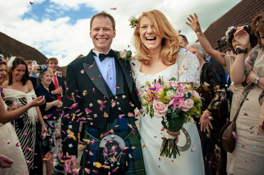 Happy bride and groom walk throw confetti at Coltsfoot