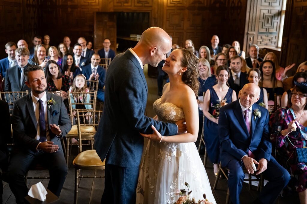 Bride and groom go in for their first kiss during the ceremony in the library at Rothamsted Manor 
