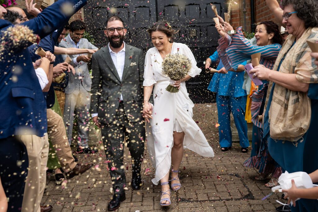 Confetti toss outside St Albans Register Office with bride holding dried flower bouquet