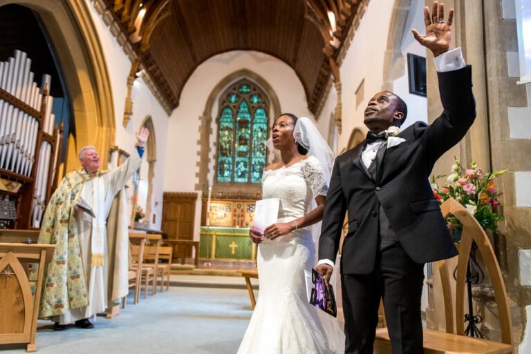Groom raises hand to heaven during evangelical church service at Hertfordshire wedding