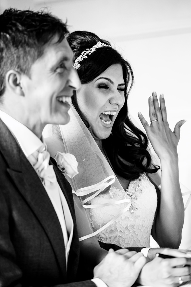 Bride shows off her ring and winks during the singing of the register at Hertfordshire wedding