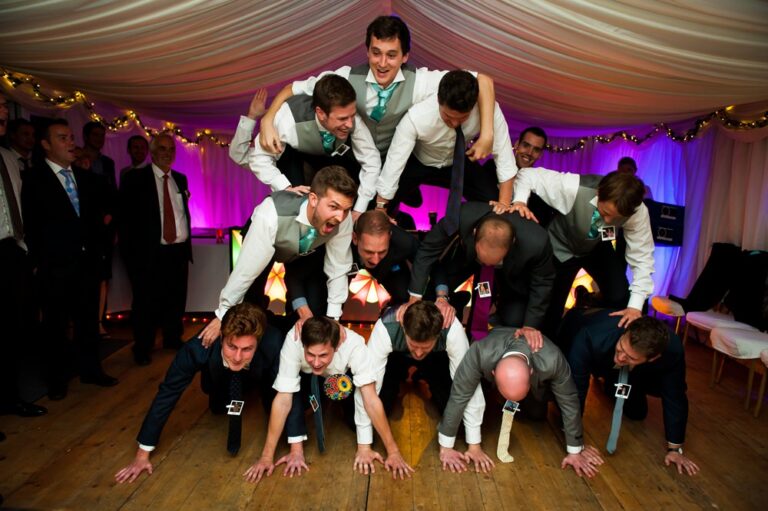 Groom, best men and friends create dance floor human pyramid at Hertfordshire marquee wedding